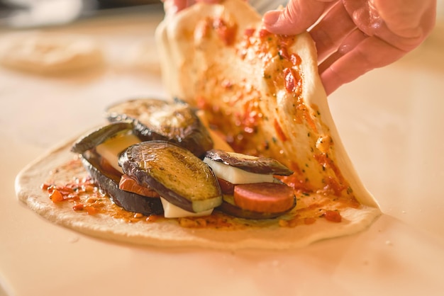 Photo gratuite les mains du chef couvrent les ingrédients sur la pâte lors de la préparation du plat italien traditionnel calzone