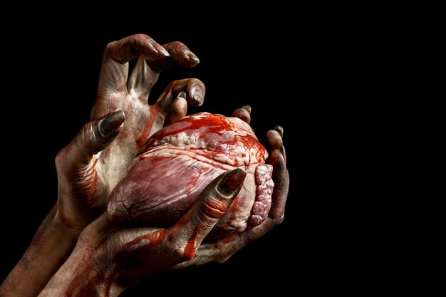 Mains effrayantes de zombie féminin tenant un coeur