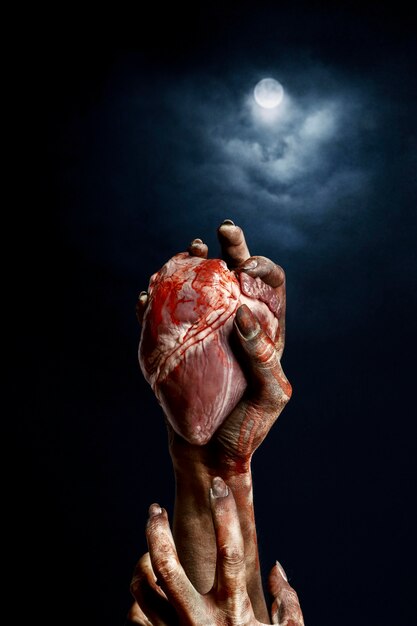 Mains effrayantes de zombie féminin tenant un coeur