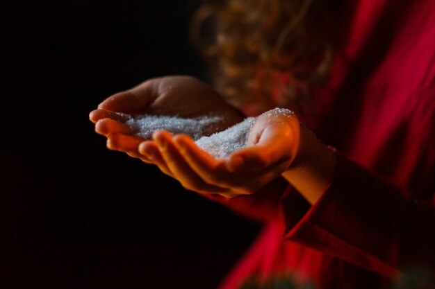 Mains d&#39;enfants tenant la neige de Noël. Concept d&#39;hiver sur fond noir.