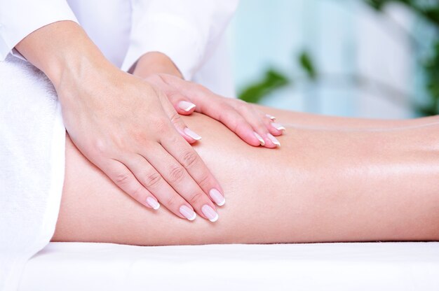 Mains de l'esthéticienne faisant un massage pour la jambe féminine