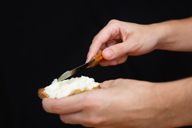 Mains étalant du fromage à pâte molle sur du pain grillé