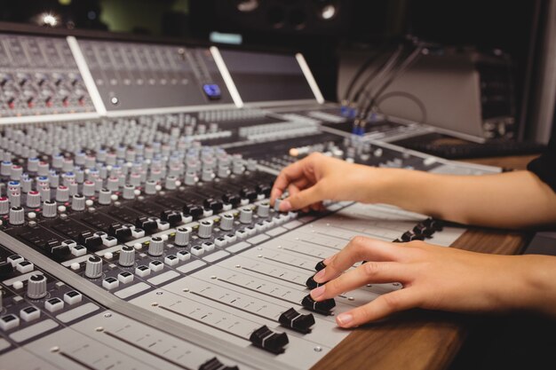 Mains d'une étudiante à l'aide d'une table de mixage sonore