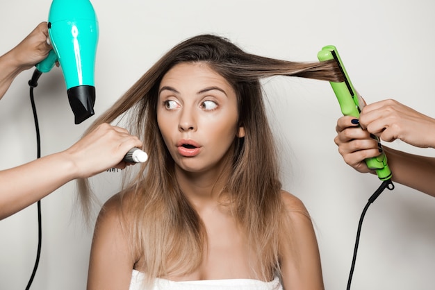 Mains faisant la coiffure à la belle jeune femme