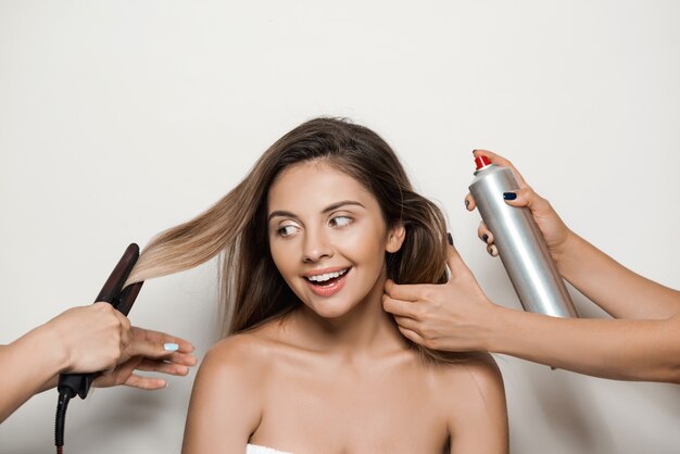 Mains faisant la coiffure à la belle jeune femme