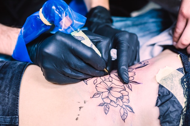 Mains faisant le tatouage avec la machine
