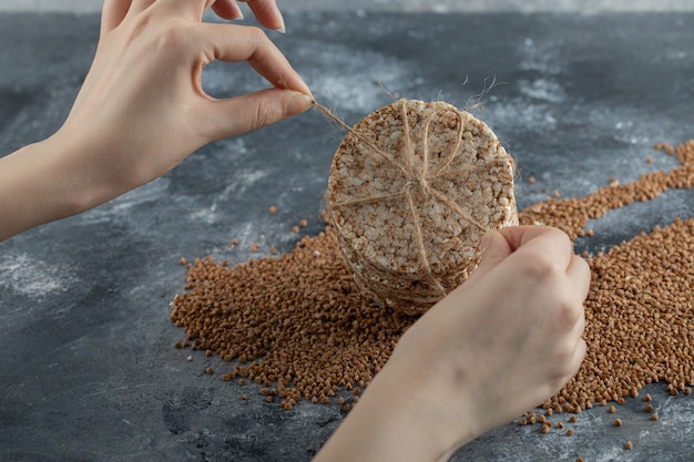 Photo gratuite mains féminines attachant le gâteau de riz sur la surface en marbre