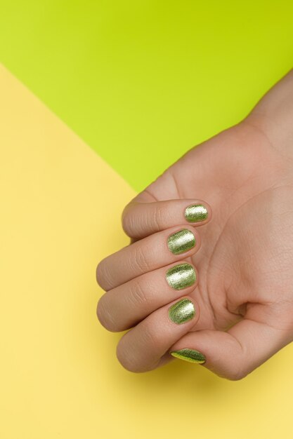 Mains féminines avec la conception des ongles verts. Vernis à ongles vert mains manucurées. Mains féminines sur fond vert