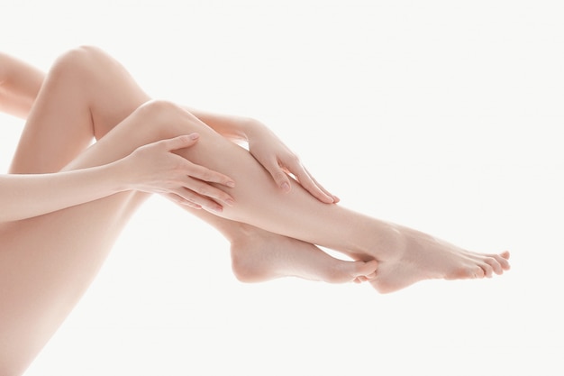 mains féminines sur les jambes, concept de soins du corps de la peau