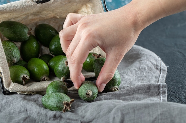 Photo gratuite mains féminines prenant des fruits de feijoa hors du panier.