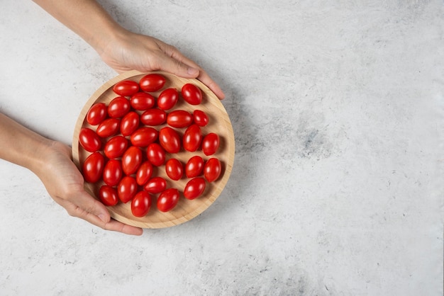 Mains féminines tenant une assiette de tomates cerises.