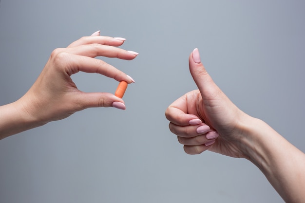 Les mains féminines tenant la capsule de pilule libre.