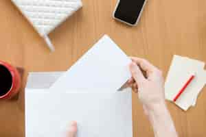 Photo gratuite les mains féminines tenant une enveloppe avec une feuille sur le bureau de