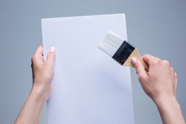 mains féminines tenant un pinceau sur toile blanche