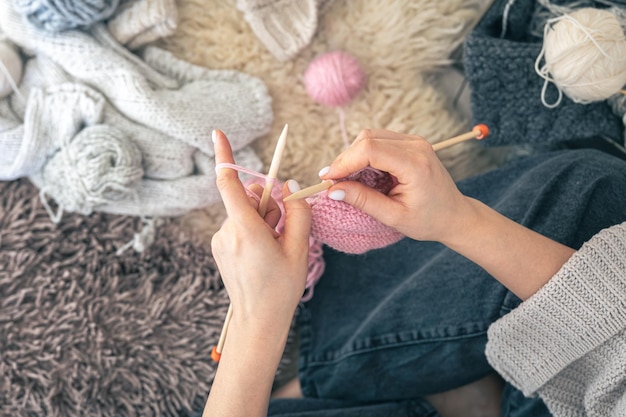 Photo gratuite des mains féminines tricotent un foulard rose chaud à la maison