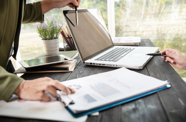 Mains de femme d'affaires à l'aide d'un ordinateur portable placé sur le bureau de bureau en désordre.