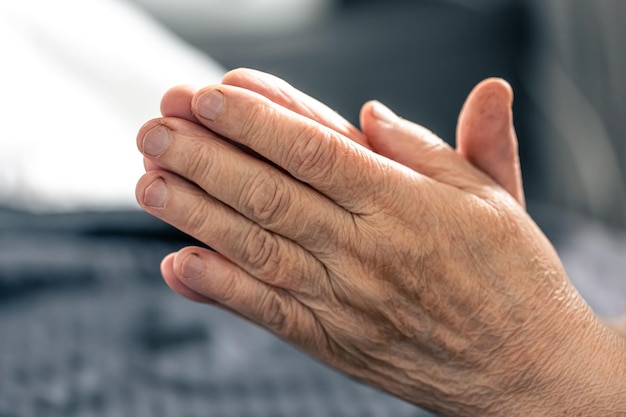 Photo gratuite les mains d'une femme âgée jointes en prière