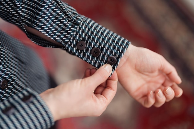 Mains de femme boutonnant le brassard sur la chemise dans une lumière douce