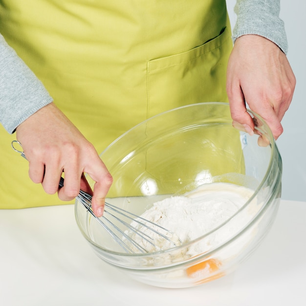 Mains de femme fouettant la pâte dans la cuisine