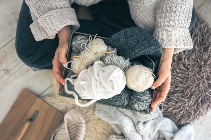 Photo gratuit des mains de femme en gros plan portant un pull en laine contenant une boîte avec des boules de fil