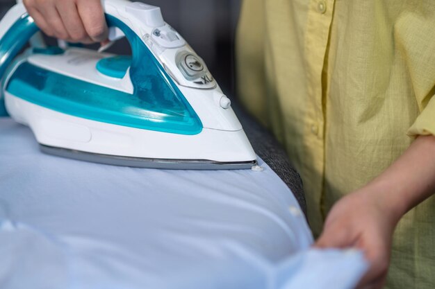 Mains d'une femme repassant des vêtements froissés