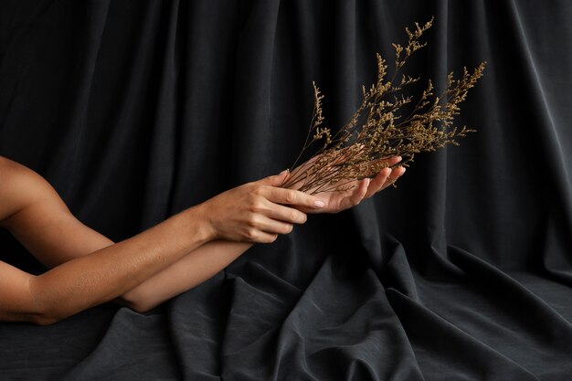 Mains de femme tenant une plante avec un rideau sombre