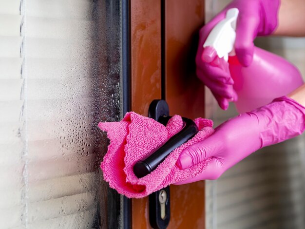 Mains avec des gants chirurgicaux, nettoyer la poignée de porte avec ablution
