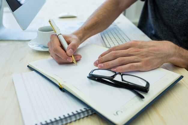 Mains de graphiste mâle écrivant sur un journal