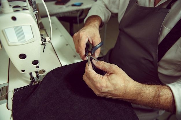 Les mains de l'homme et la machine à coudre. Atelier de cuir. Textile vintage industriel. L'homme au métier féminin. Concept d'égalité des sexes
