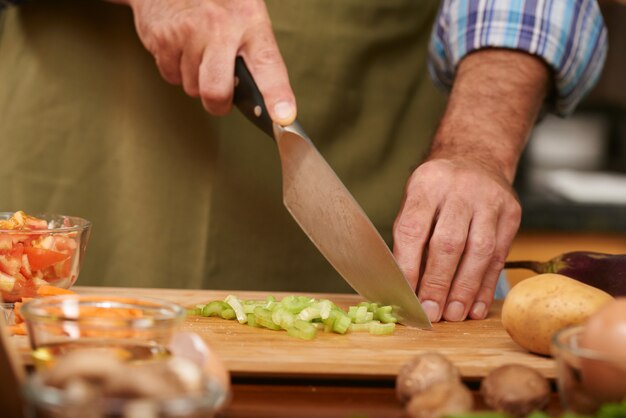 Mains d'homme méconnaissable découpant des légumes frais