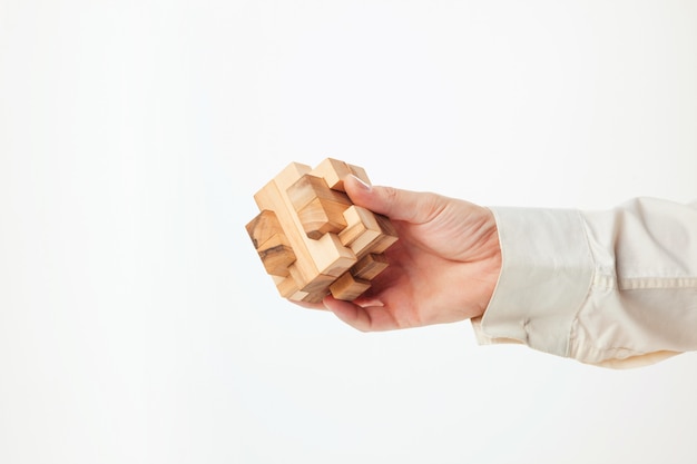 Les mains de l'homme tenant un puzzle en bois.