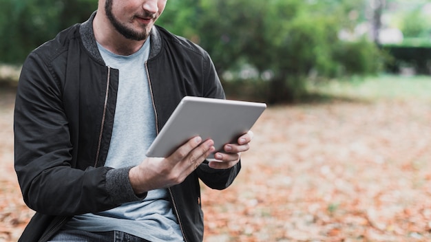 Mains d'homme tenant une tablette dans le parc