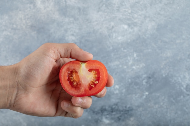 Mains d'homme tenant une tranche de tomate rouge. Photo de haute qualité