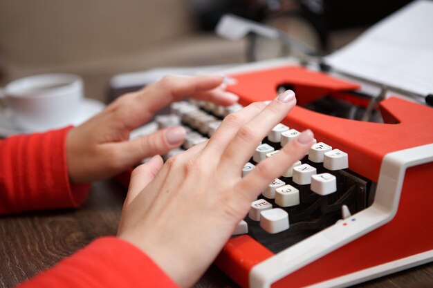 Mains humaines écrivant sur la machine à écrire rouge