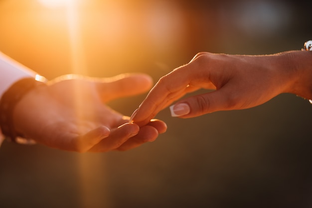 Les mains des jeunes mariés se touchent affectueusement