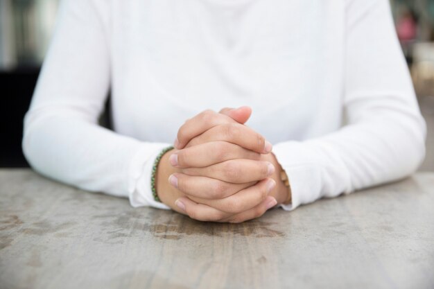 Les mains jointes de la jeune femme d&#39;affaires assis à table