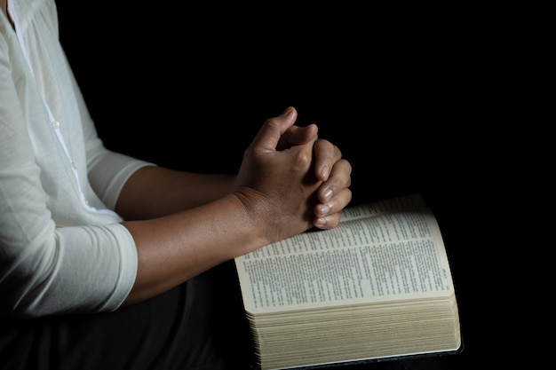 Les mains jointes en prière sur une Sainte Bible à l'église