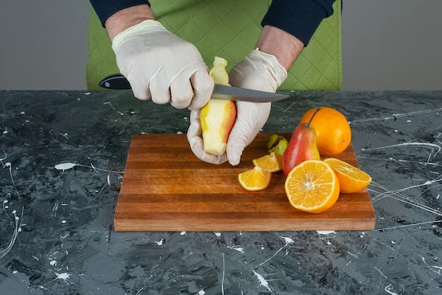 Photo gratuite mains mâles coupant la poire mûre sur la table en marbre.