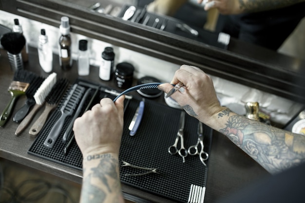 Les mains mâles et les outils pour couper la barbe au salon de coiffure.