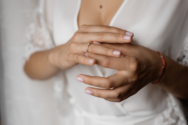 Mains d'une mariée avec une bague de fiançailles avec diamant et une manucure tendre