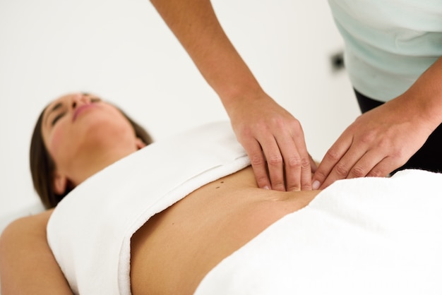 Mains massant abdomen femelle. Thérapeute appliquant une pression sur le ventre.