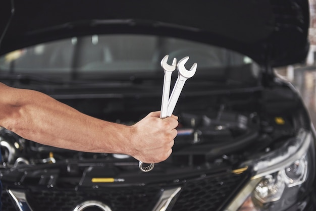 Mains de mécanicien automobile avec clé dans le garage.