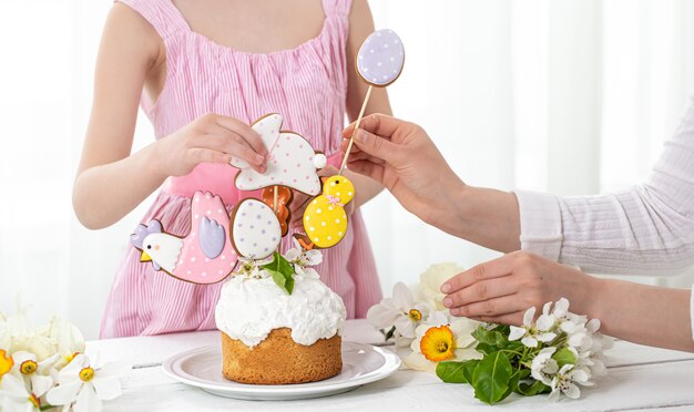 Mains d'une petite fille et mère en train de décorer un gâteau de fête. Le concept de la préparation des vacances de Pâques.