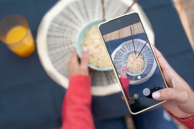 Mains prenant des photos de nouilles à plat