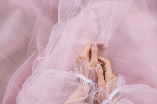 Mains sur une robe élégante rose pose.