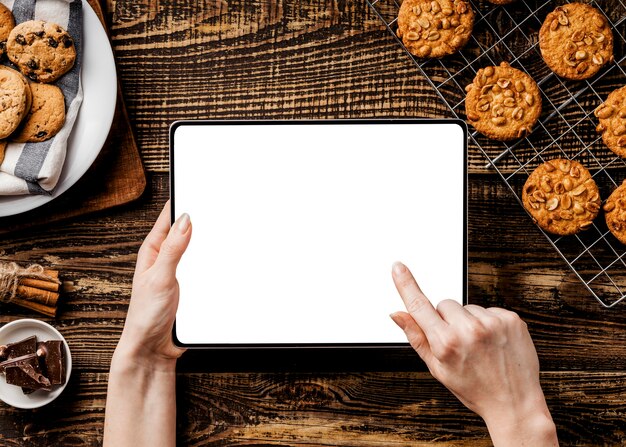 mains avec tablette et délicieux biscuits à côté