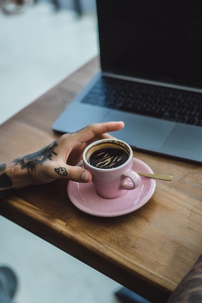 mains tatouées, café et ordinateur portable