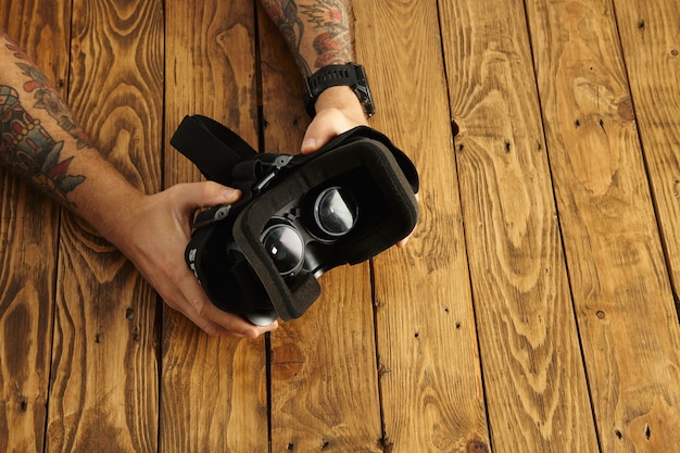 Les mains tatouées tiennent les lunettes VR à l'envers, présentation de la nouvelle technologie