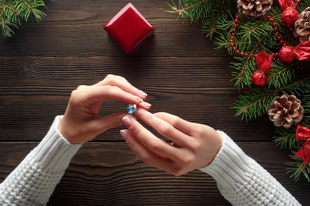 Mains tenant une bague avec une pierre bleue