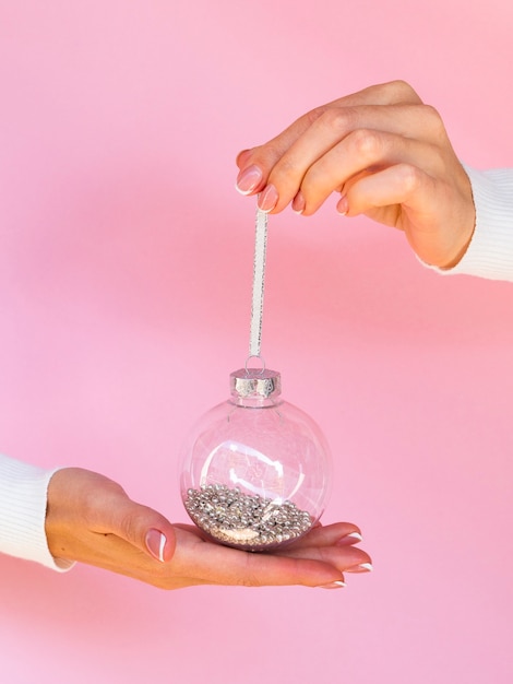 Mains tenant une boule de Noël avec des paillettes